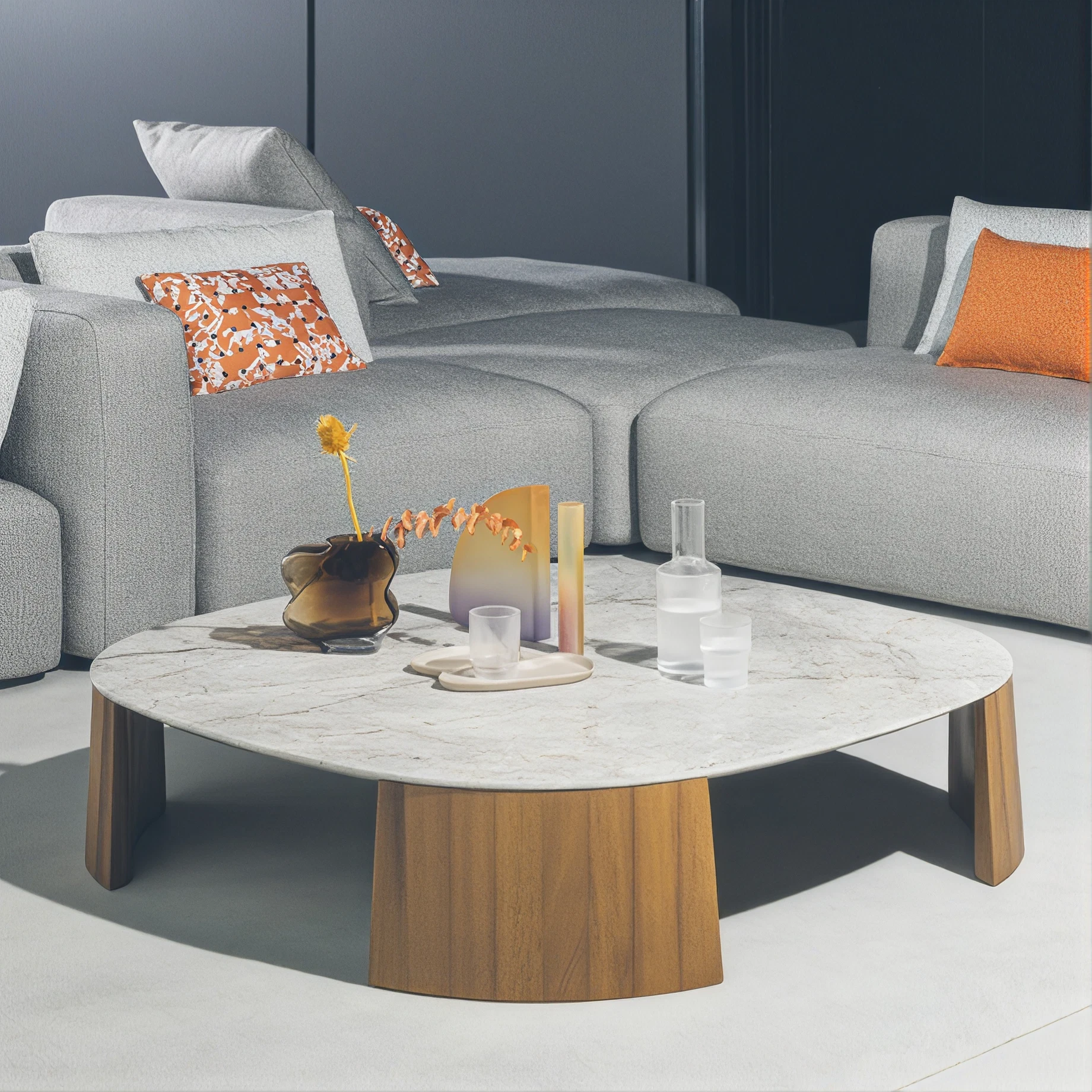 Grey modular sofa with orange cushions beside a stone-topped wooden coffee table.