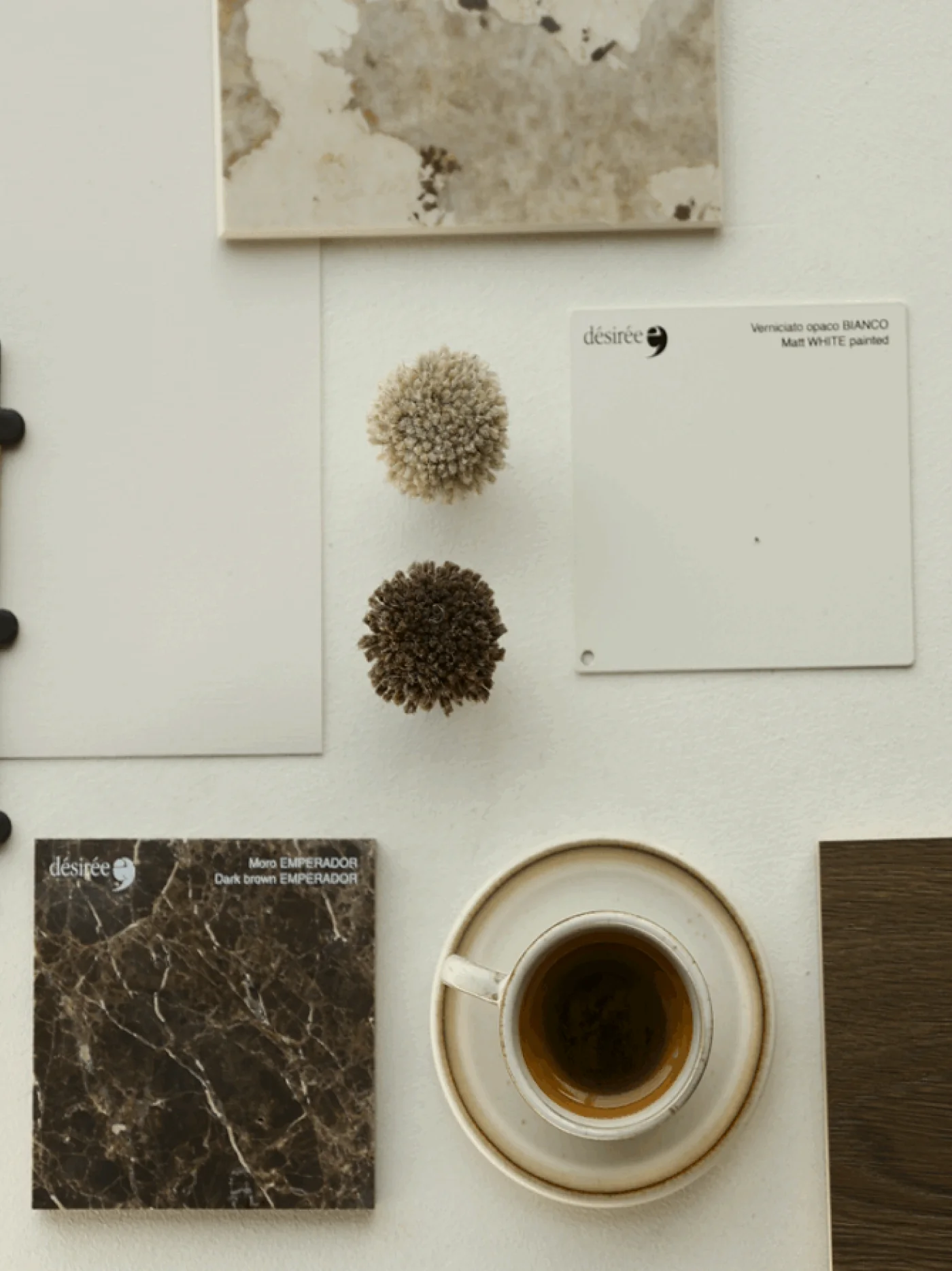 Stone, textile, painted finish and wood samples arranged beside a cup of coffee.