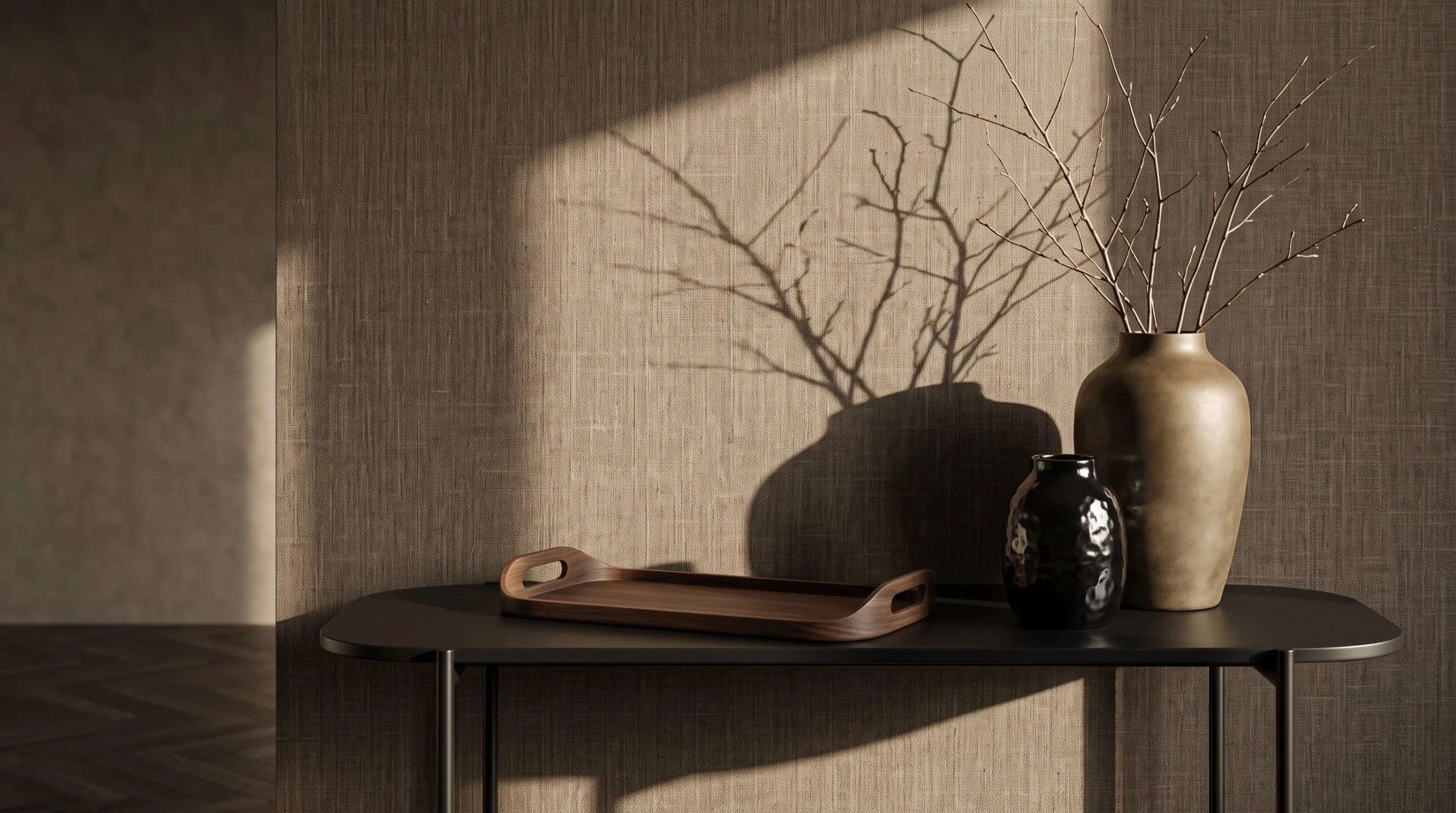 Branch shadows across textured wallcovering above a console with decorative vases.