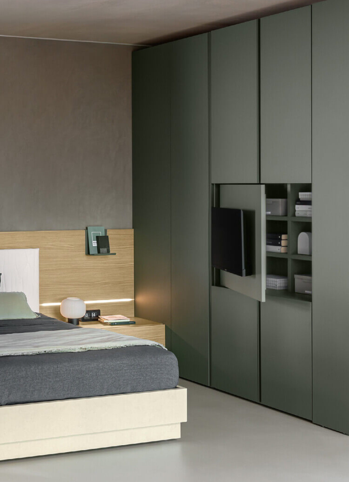 Green full-height wardrobe with integrated shelving beside an oak bed