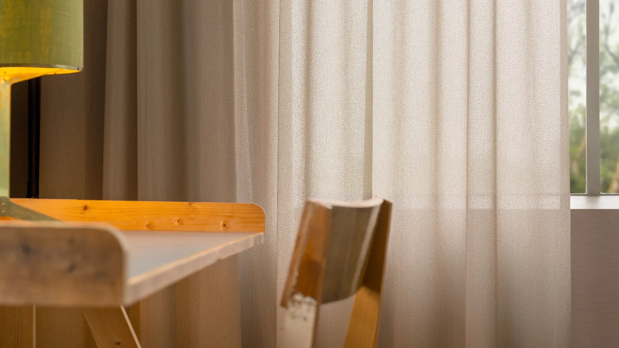 Textured sheer curtains filtering daylight beside a wooden dining table and chair.