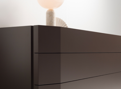 Dark wood chest of drawers with a pale sculptural table lamp