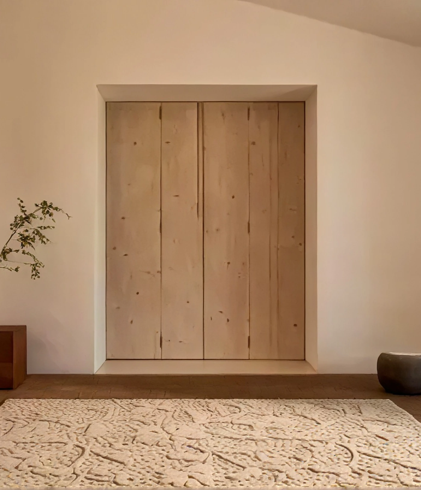 Textured cream rug in front of pale wooden double doors.